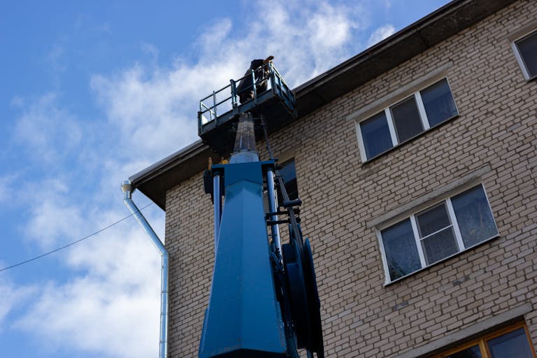 Low angle shot of a brick building exterior with a construction crane reaching the roof.